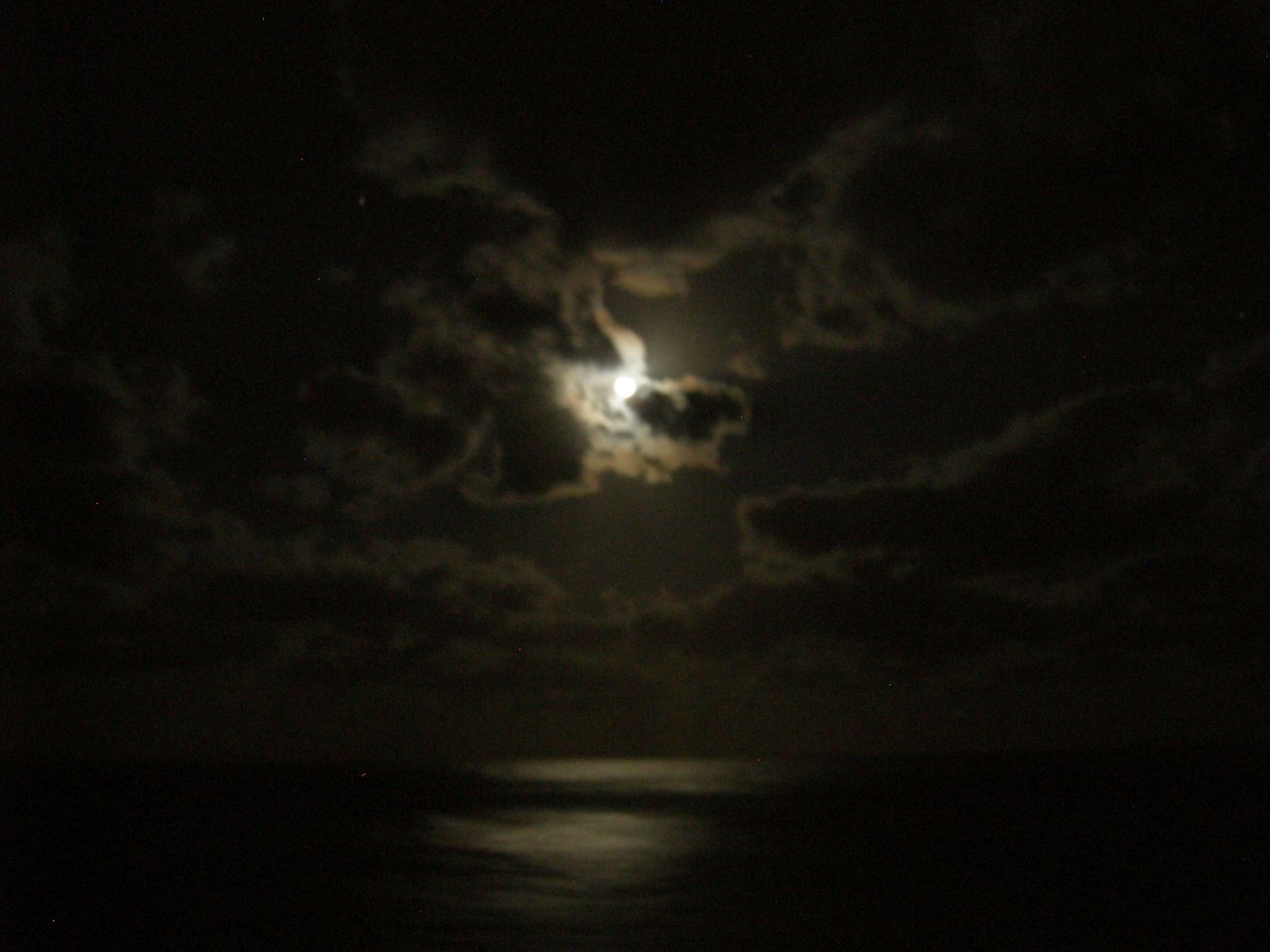 The moon was glowing through the clouds.