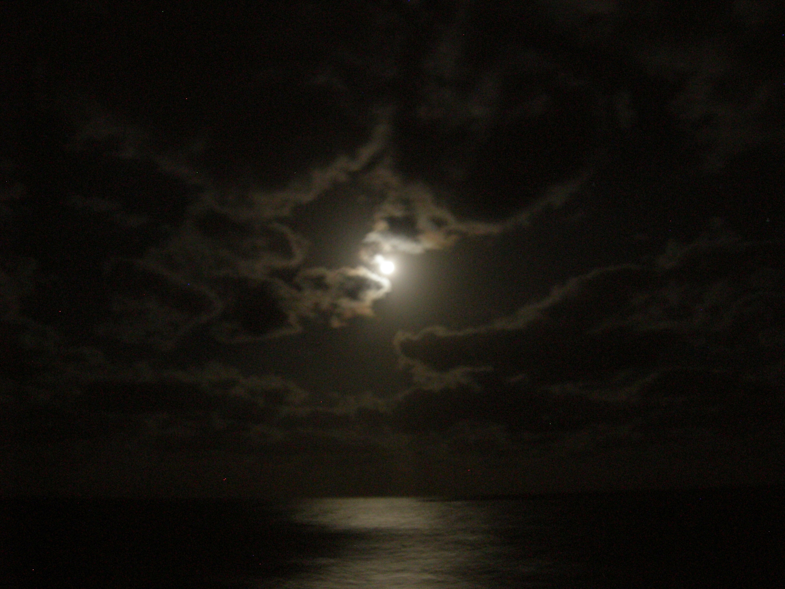 The moon was glowing through the clouds.