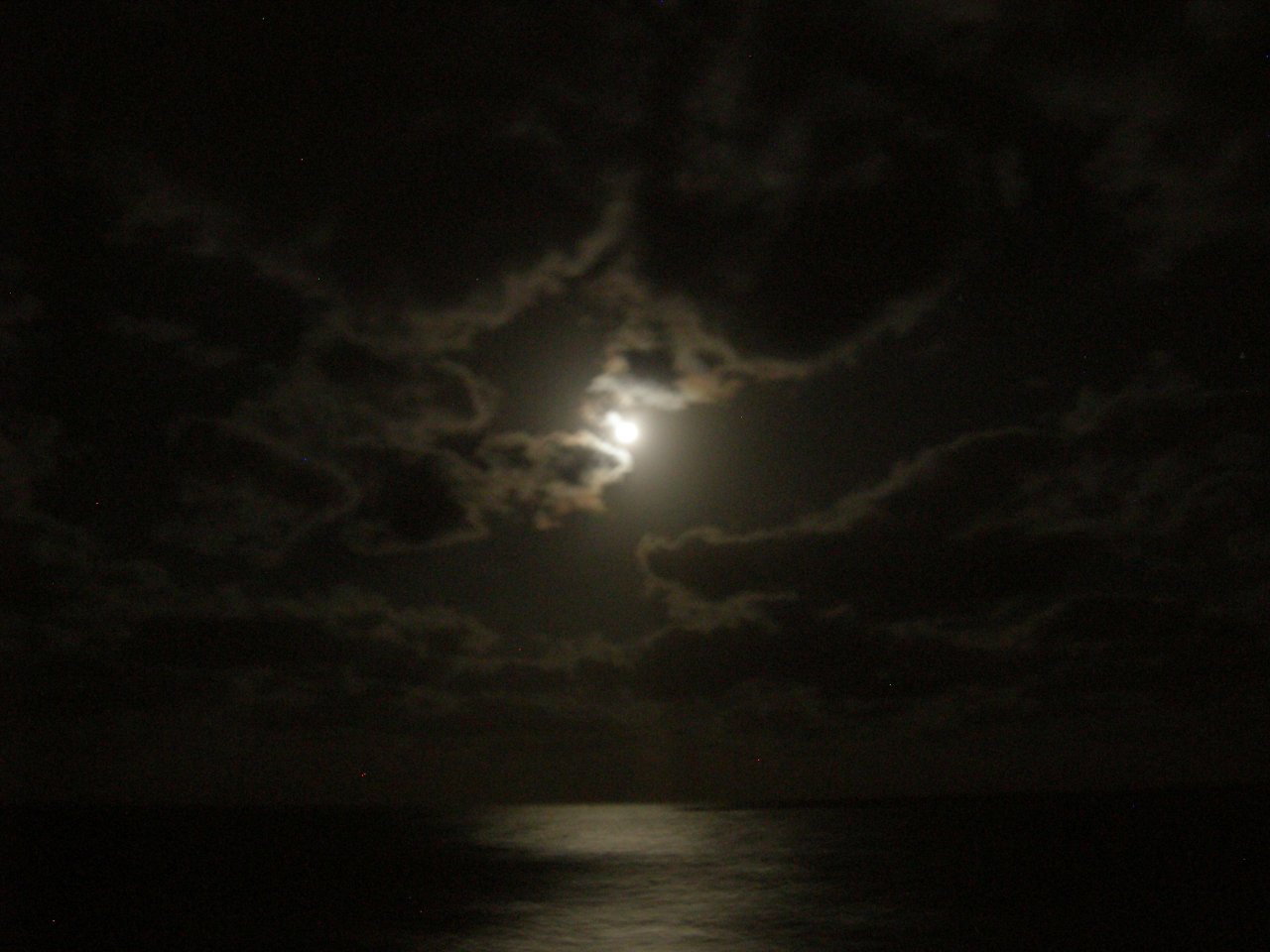 The moon was glowing through the clouds.