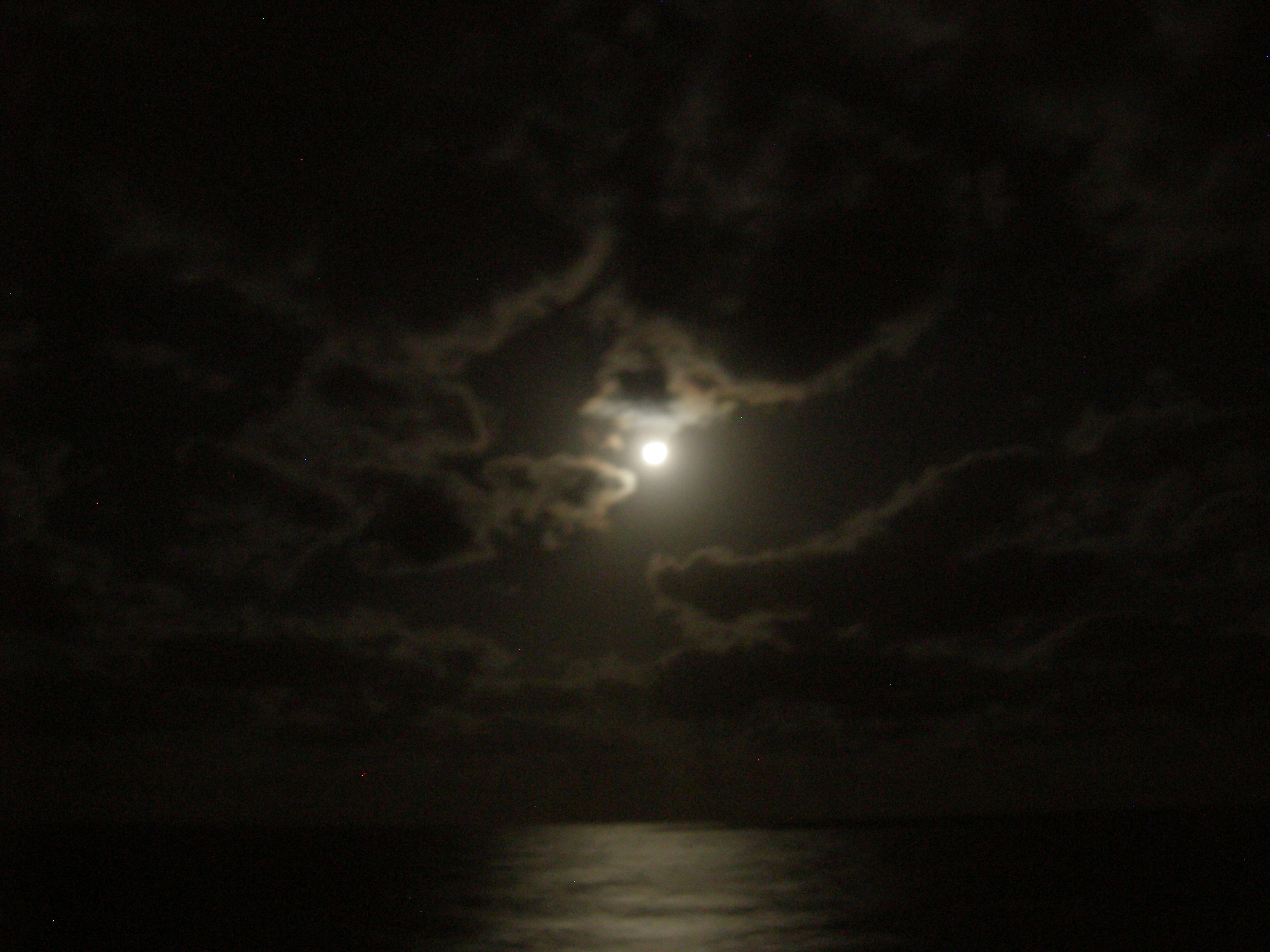 The moon was glowing through the clouds.