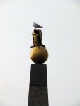 a bird perching on a statue in the market square