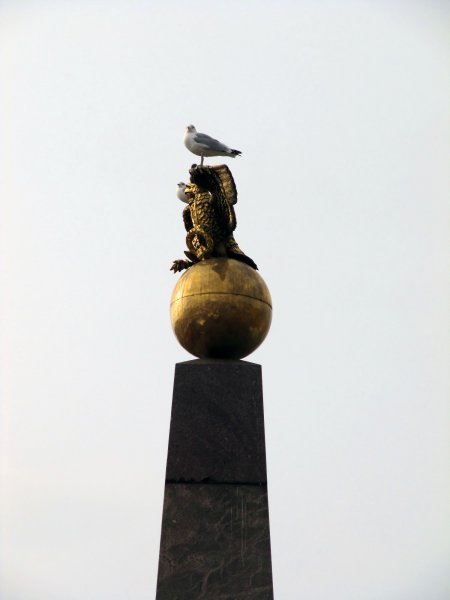 a bird perching on a statue in the market square
